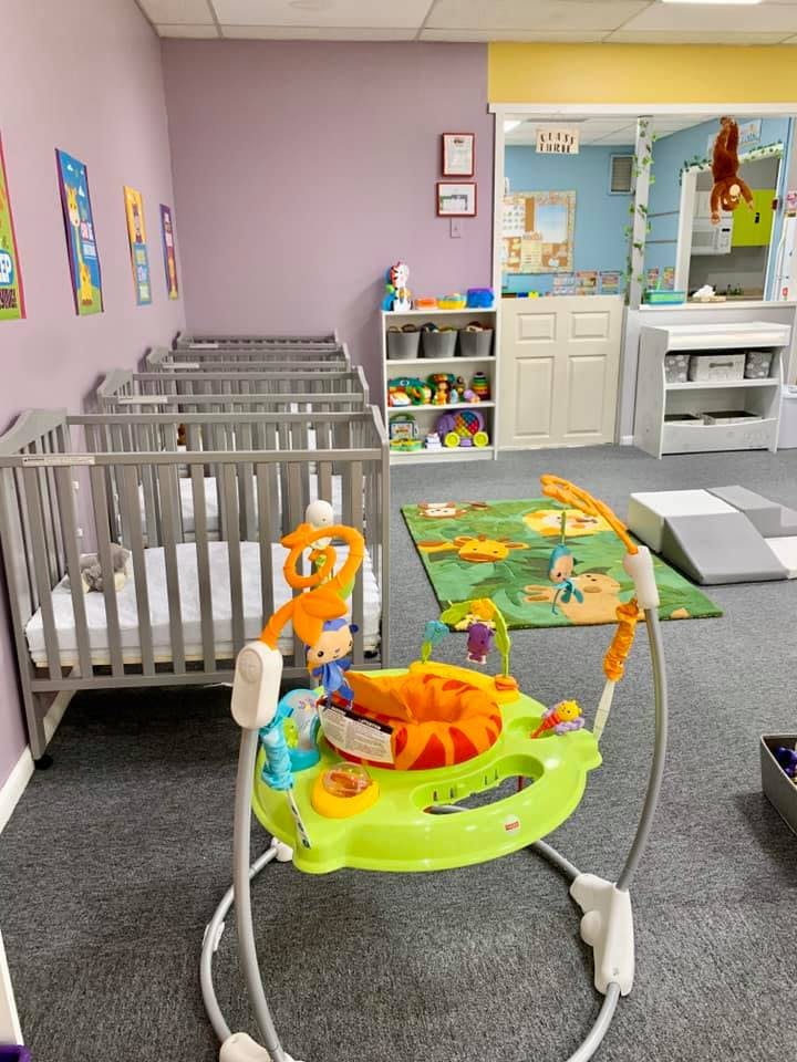 Nursery room with multiple cribs and a baby activity center