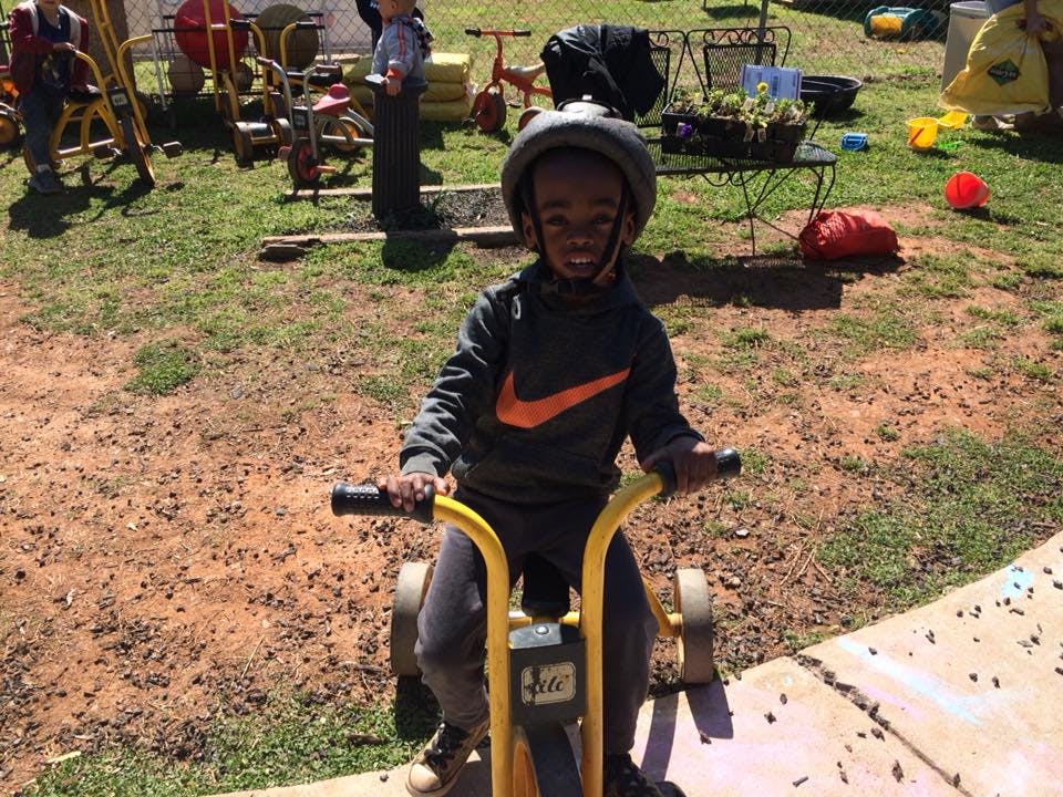 Child wearing a helmet riding a tricycle outdoors
