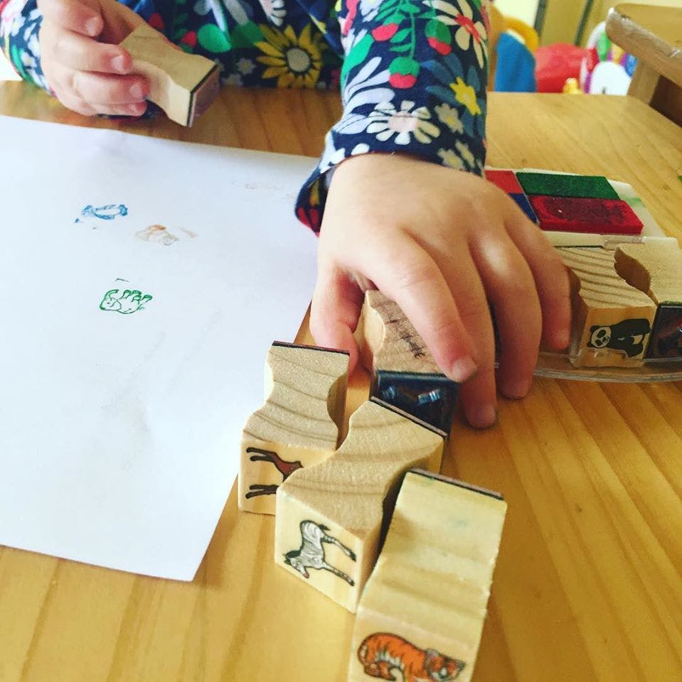 Child's hands playing with wooden stamps on paper