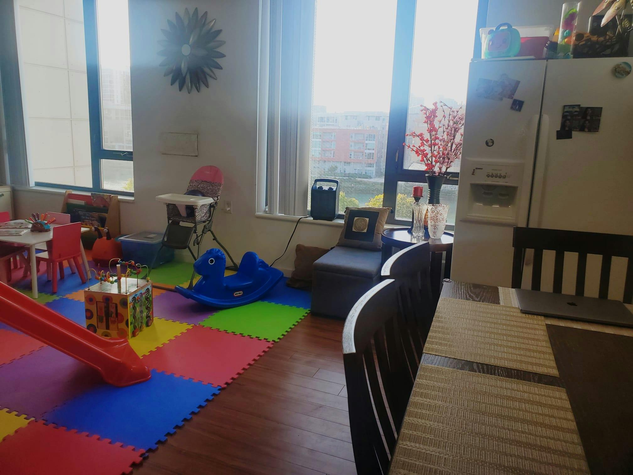 Play area with colorful floor mats, a red slide, and a blue rocking toy