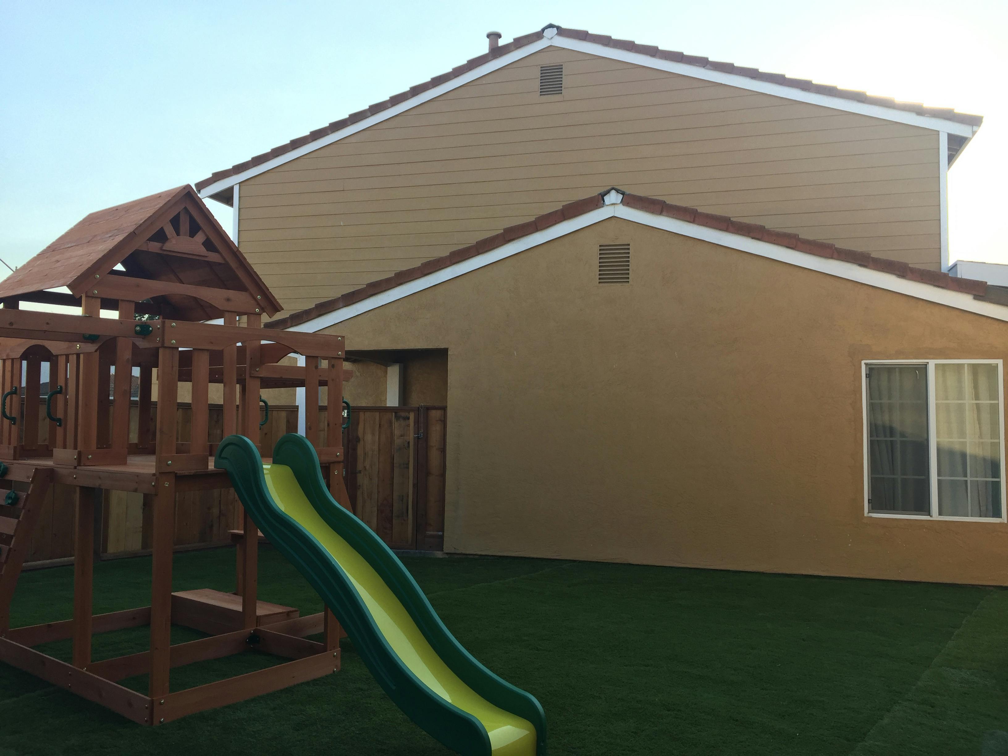 Play structure with slide in a yard next to a house