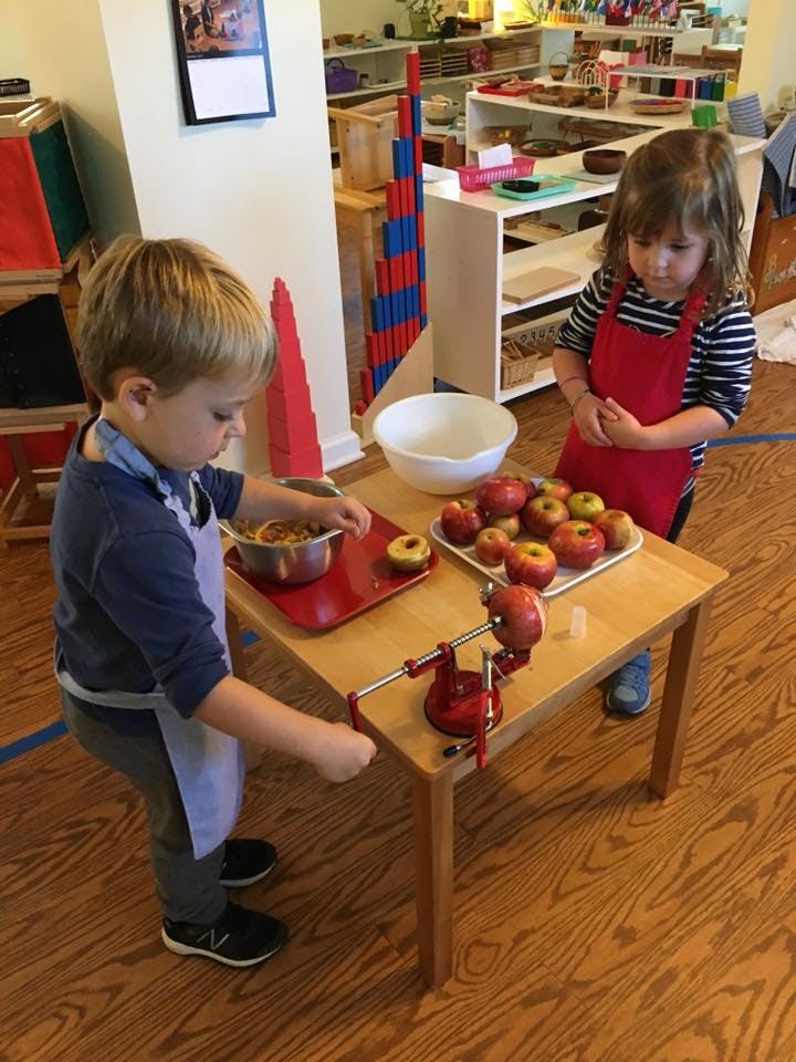 Two children peeling apples at a small table