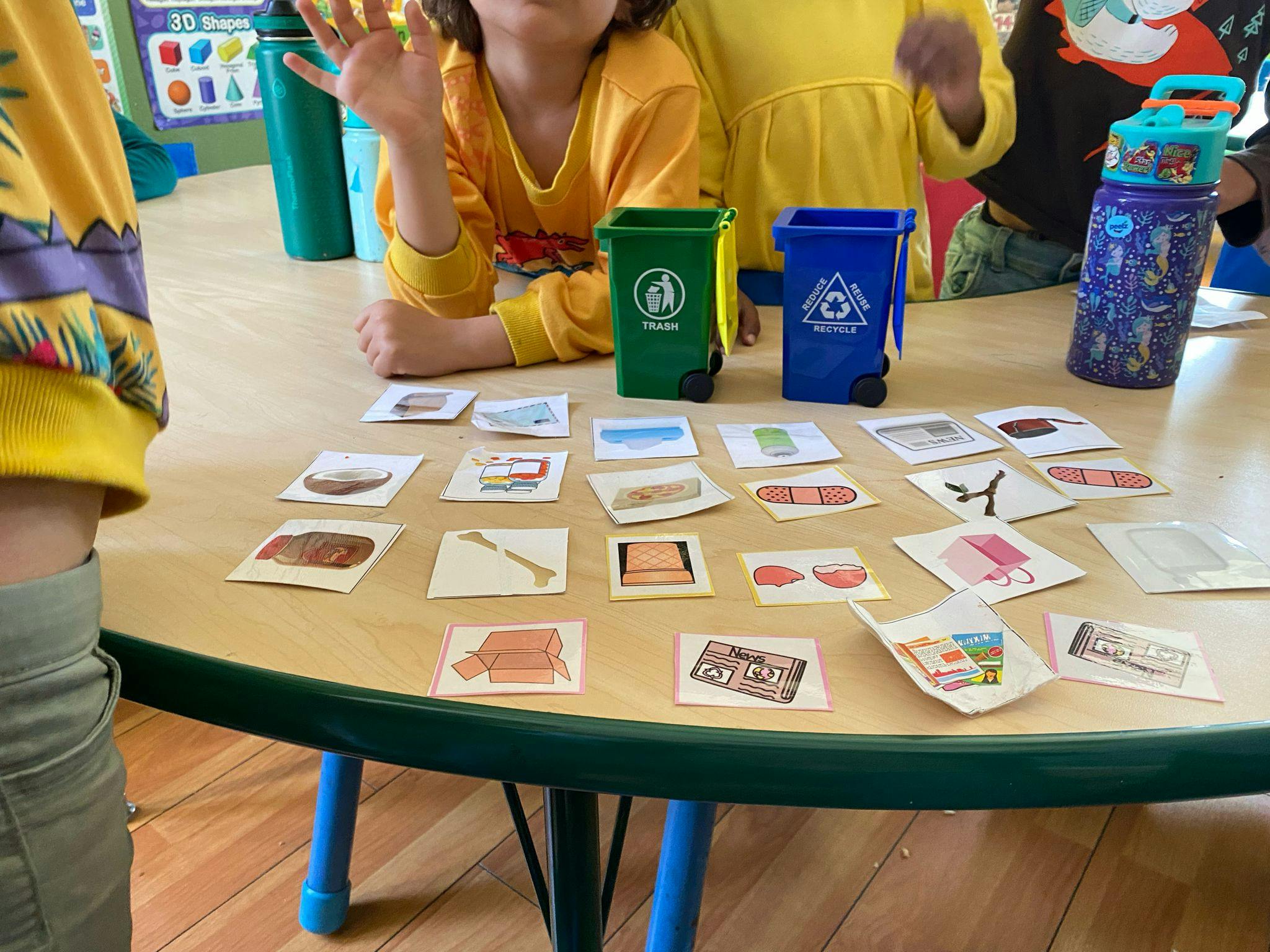 Children at a table with sorting cards and miniature recycling bins
