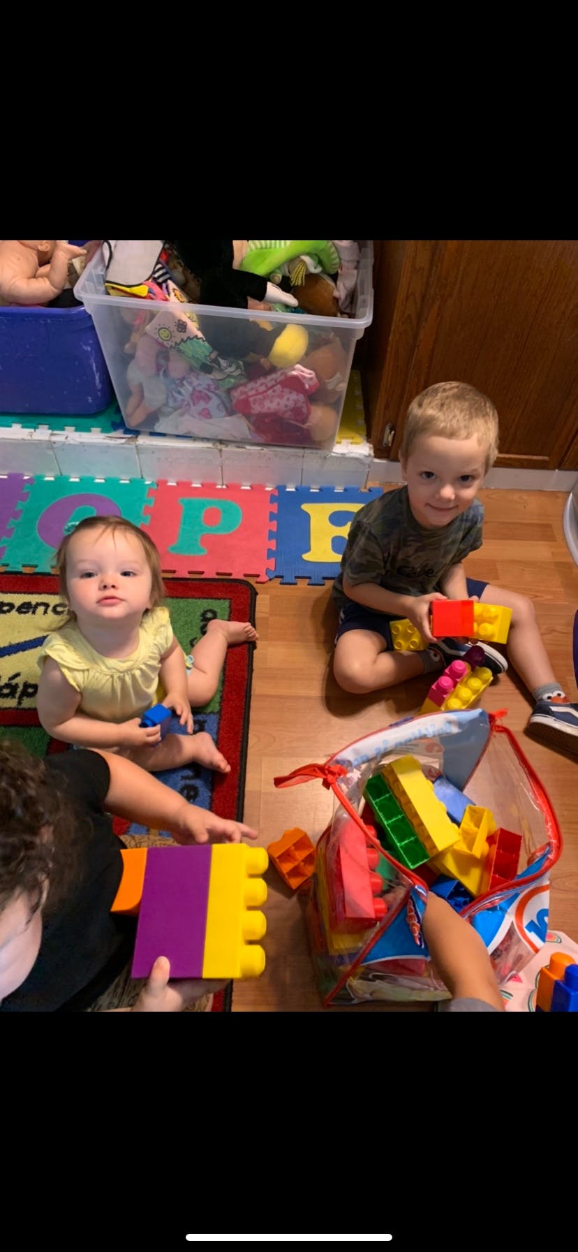 Two children playing with building blocks on a mat