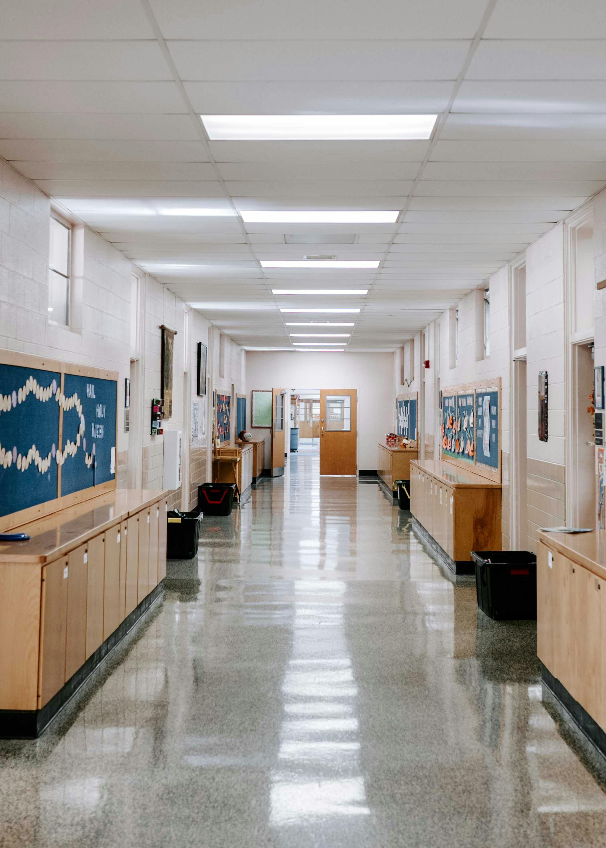 Empty school hallway with bulletin boards and wooden cabinets
