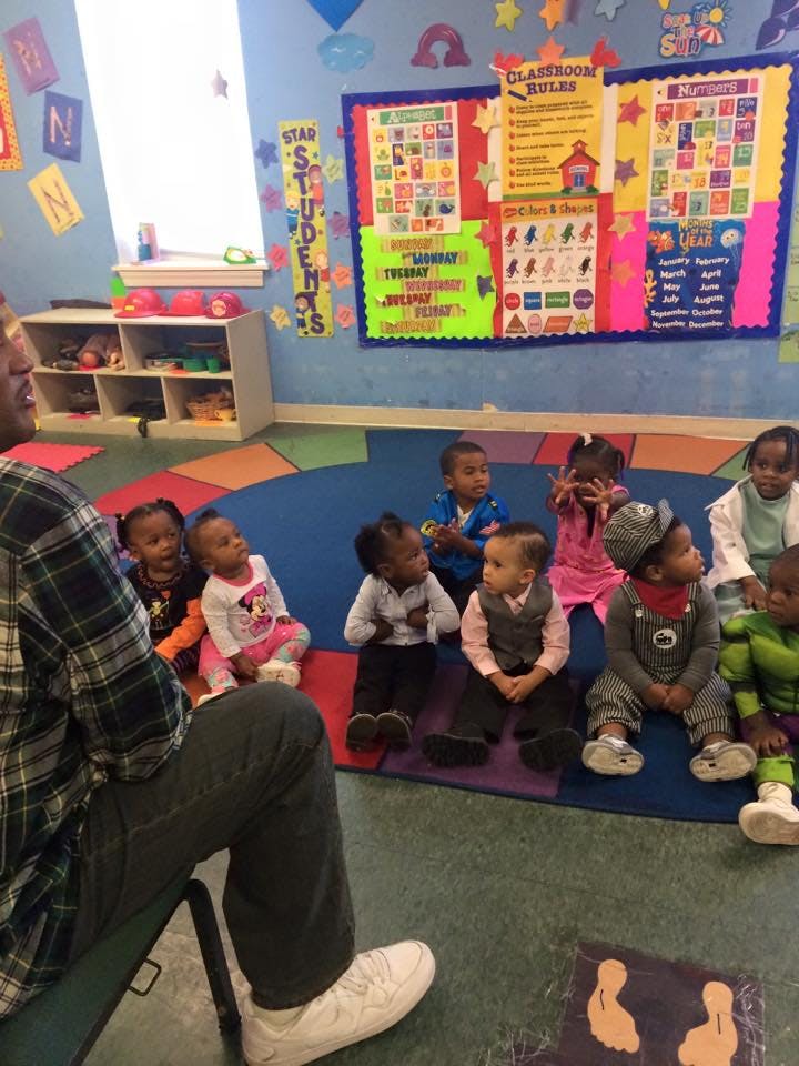 Adult sitting on floor with a group of young children