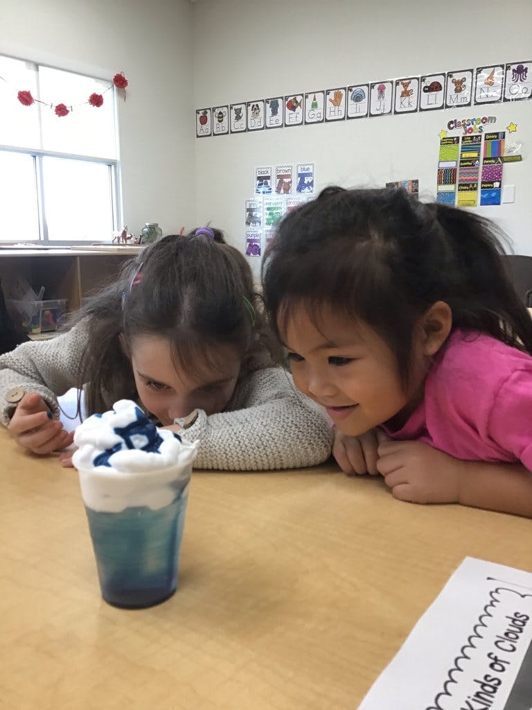 Two children looking at a cup with blue liquid and white foam