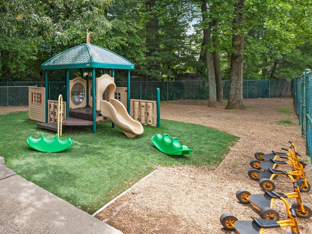 Outdoor playground with a play structure, slides, and tricycles