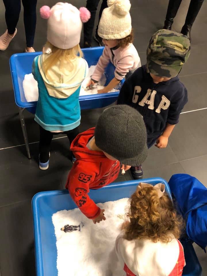 Children playing with white material in blue bins