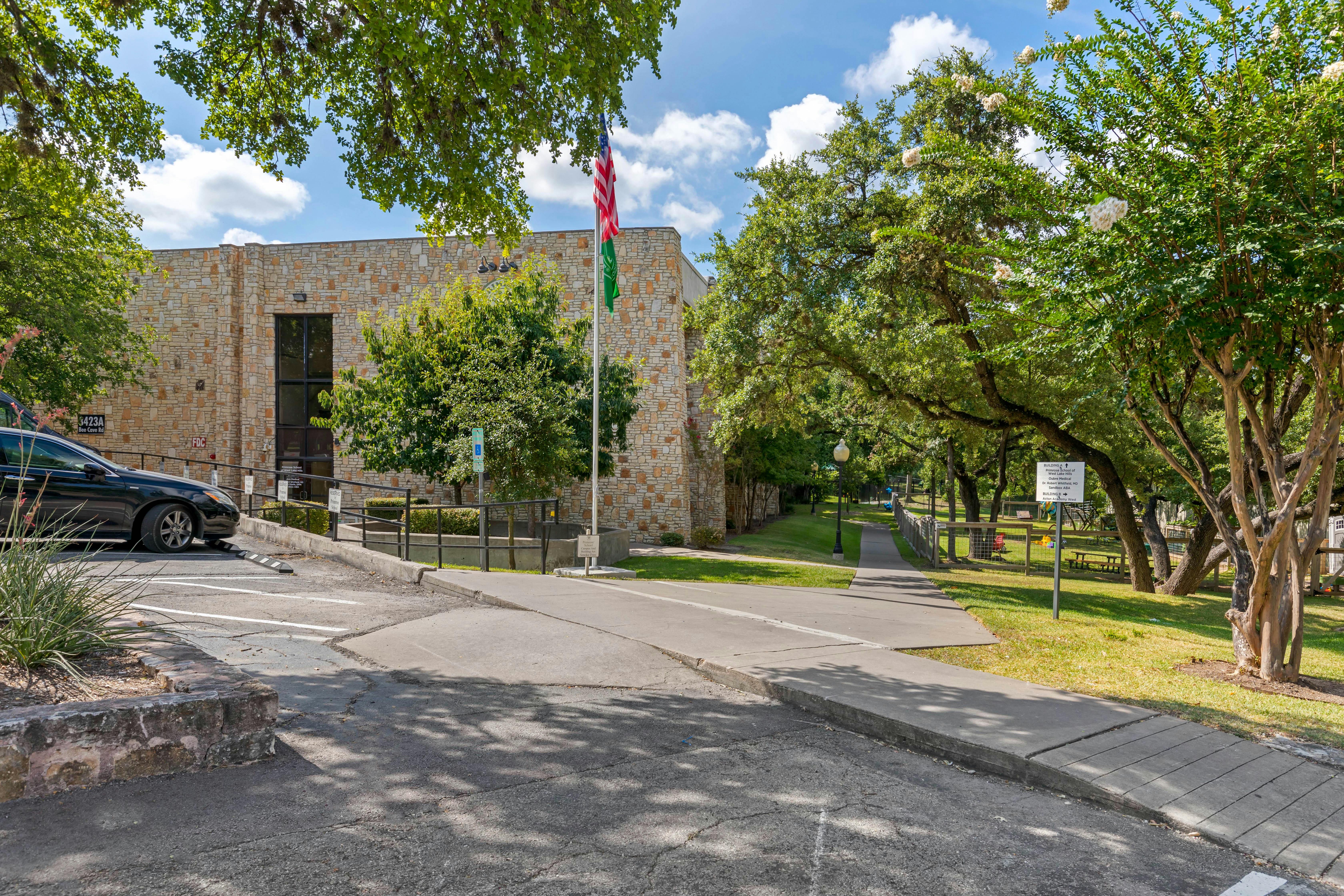 stone building with a car parked outside and a flag flying overhead