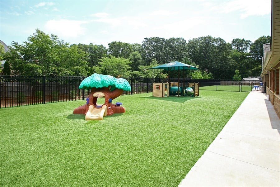Outdoor playground with a tree-shaped slide and a shaded play structure