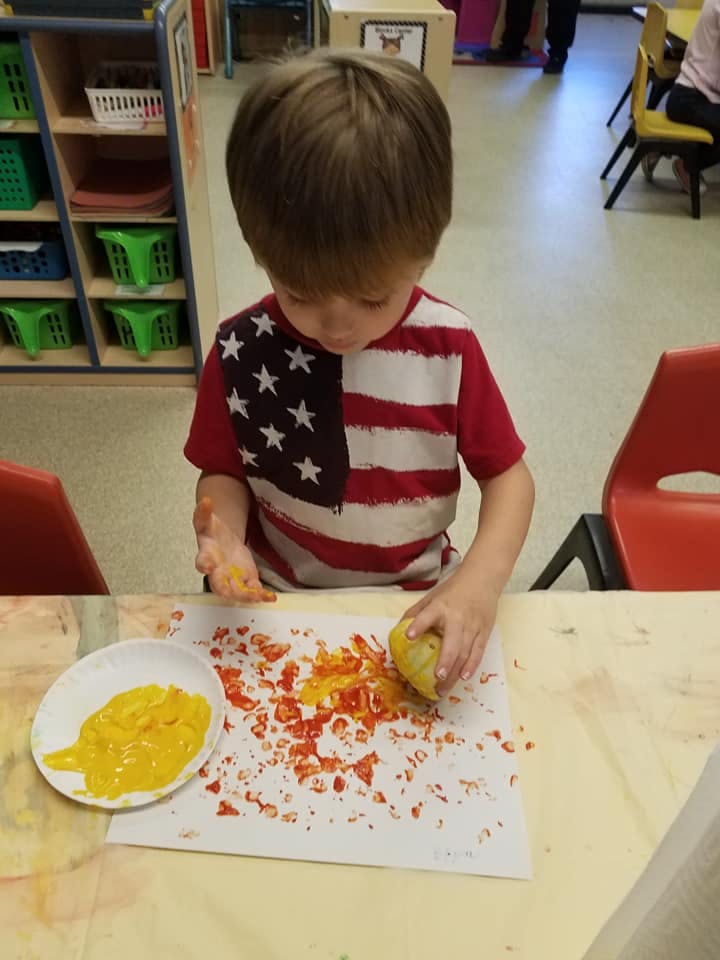 Child in a classroom doing an art project with paint