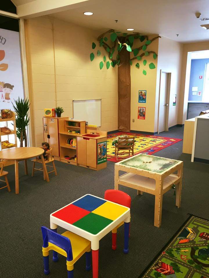 Colorful playroom with small tables and chairs, a tree decoration on the wall