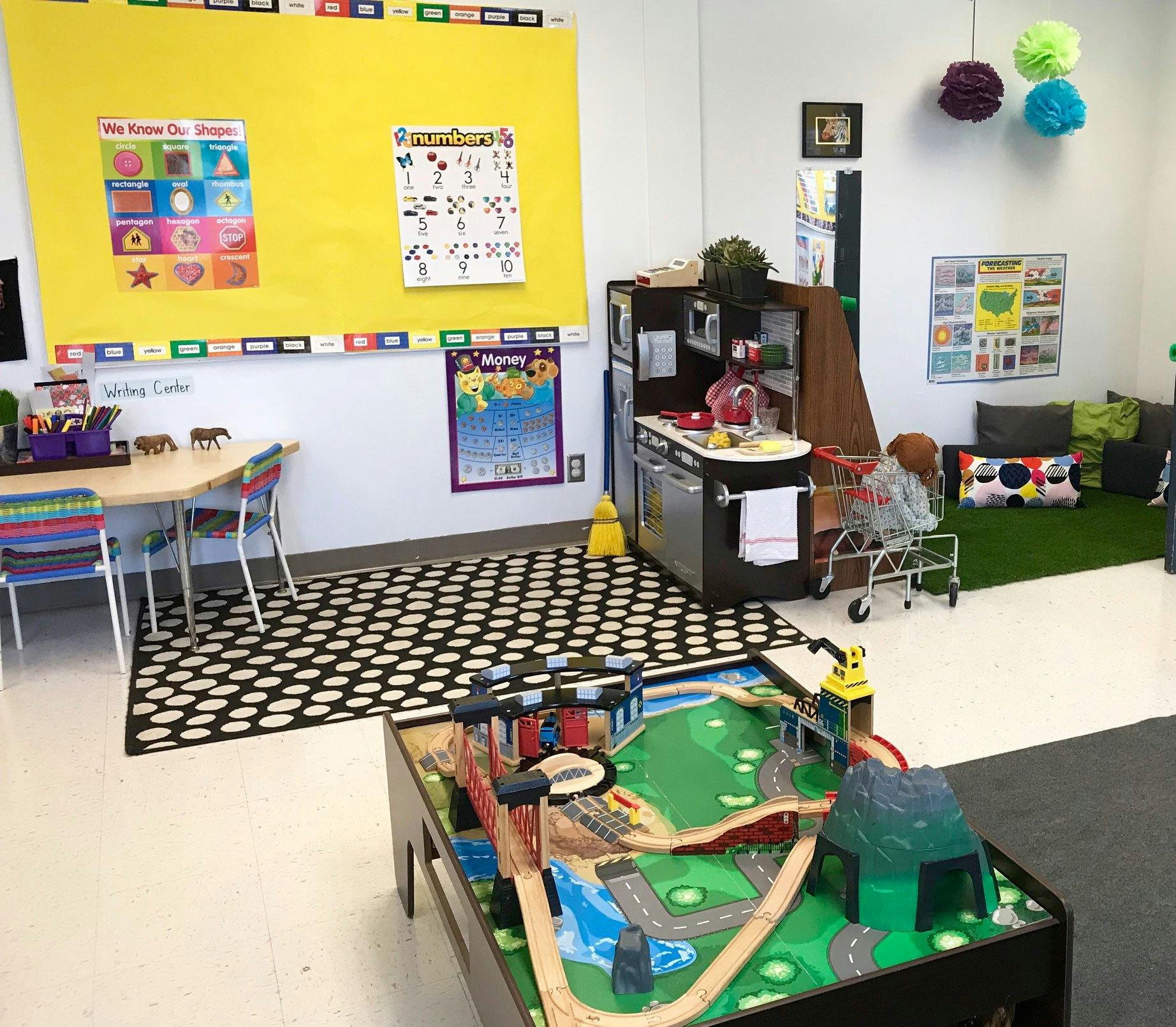 Playroom with a train table, play kitchen, and small table with chairs