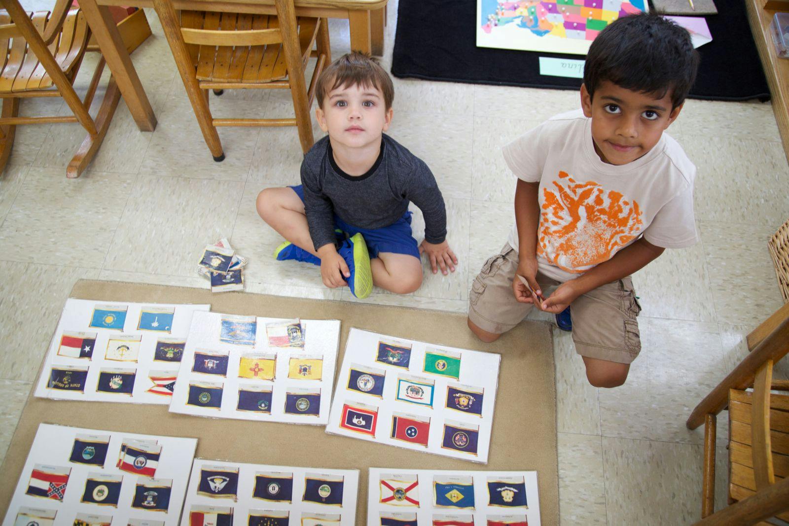 Two children on the floor with flag cards