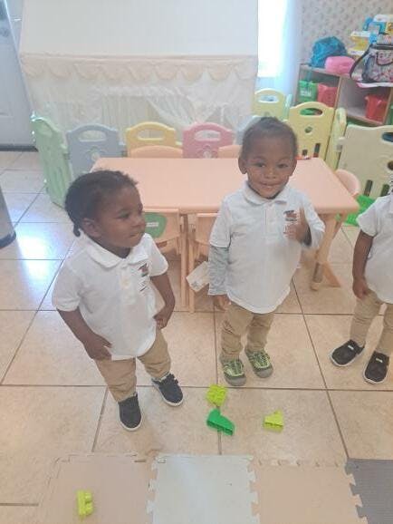Two children standing in a room with a small table and chairs