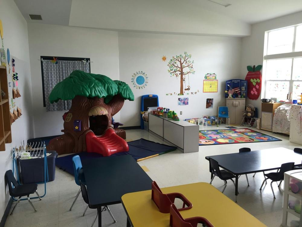 Indoor play area with a tree-shaped slide, tables, and chairs