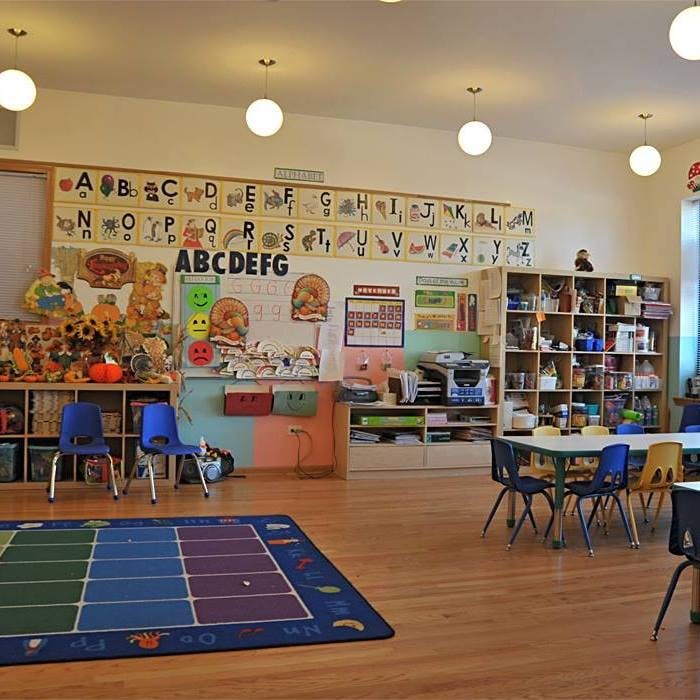 Classroom with alphabet charts, colorful rug, and small tables with chairs