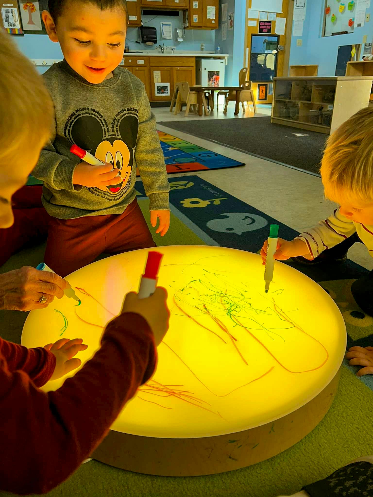 Children drawing on a light table in a classroom