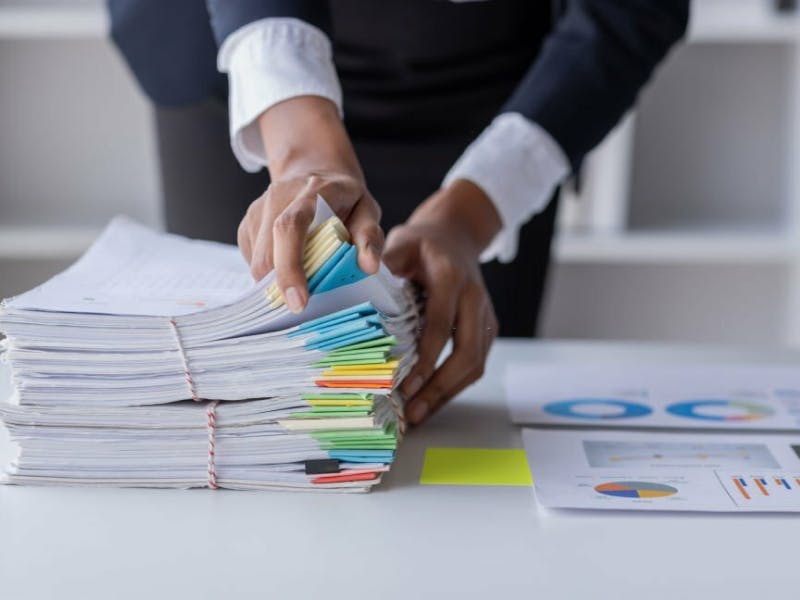 Person sorting through a stack of documents with colorful divider tabs
