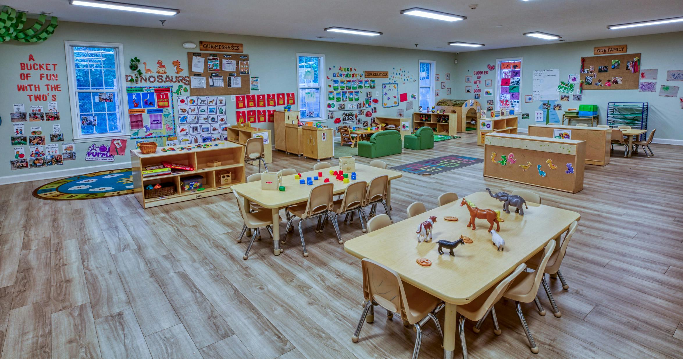 Childcare classroom with tables, chairs, colorful decorations, and toys