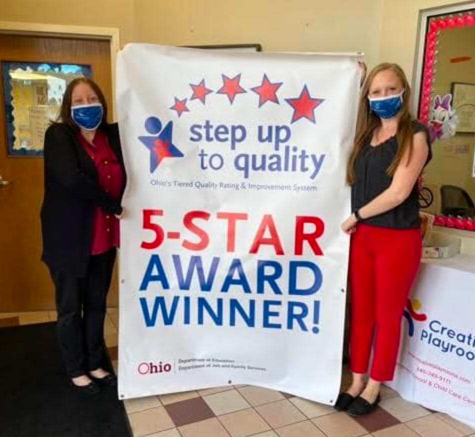 Two people wearing masks holding a banner that reads "5-STAR AWARD WINNER!"