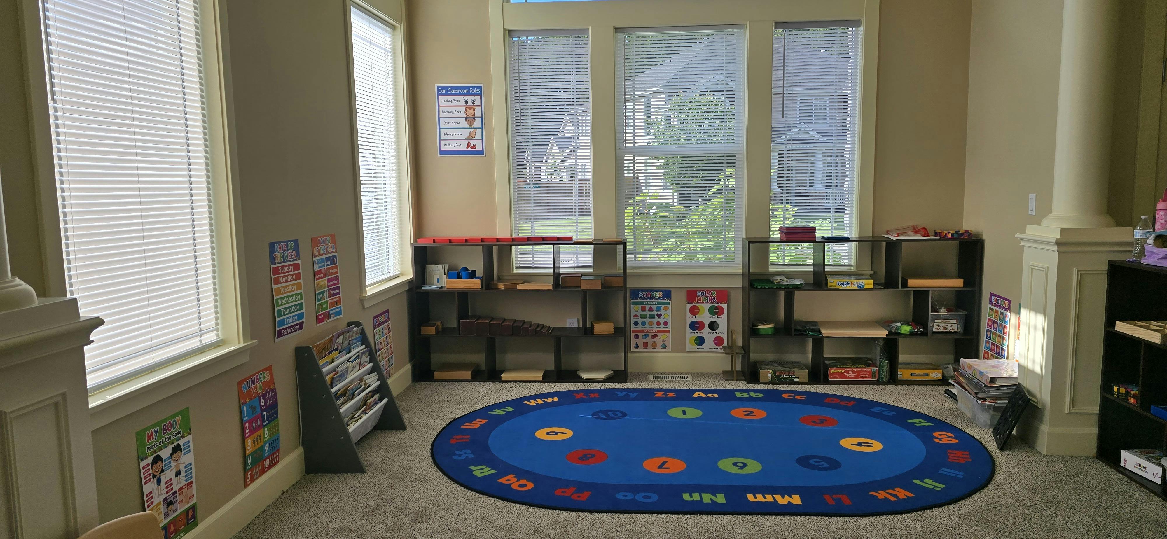 Classroom with learning materials on shelves, posters on walls, and an alphabet rug