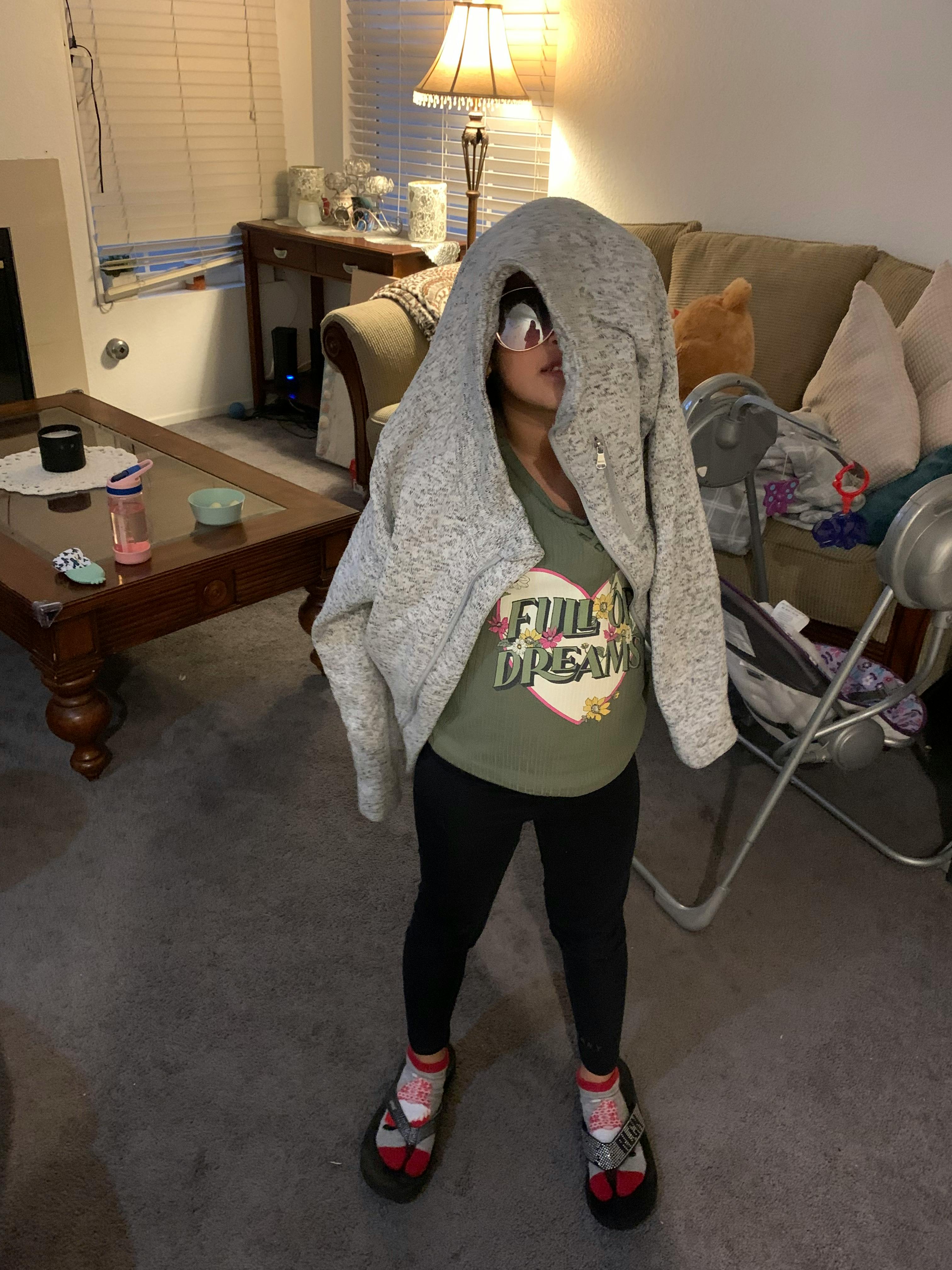Person wearing a hooded sweatshirt over their head and sunglasses