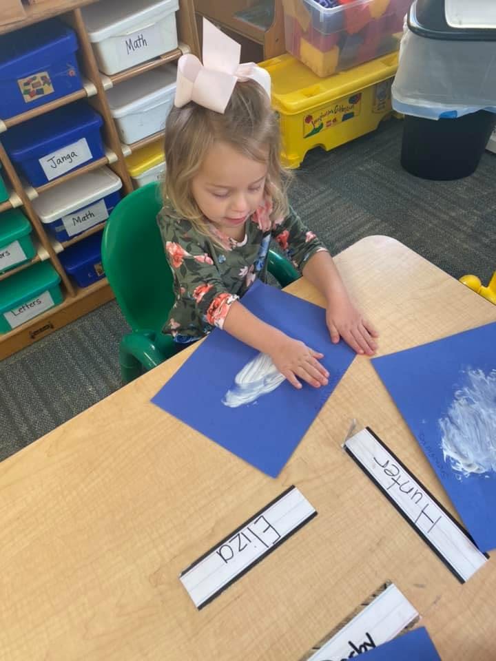 Child painting on blue paper at a table