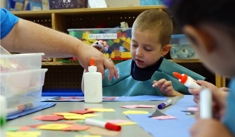 Child and adult doing crafts with glue and paper