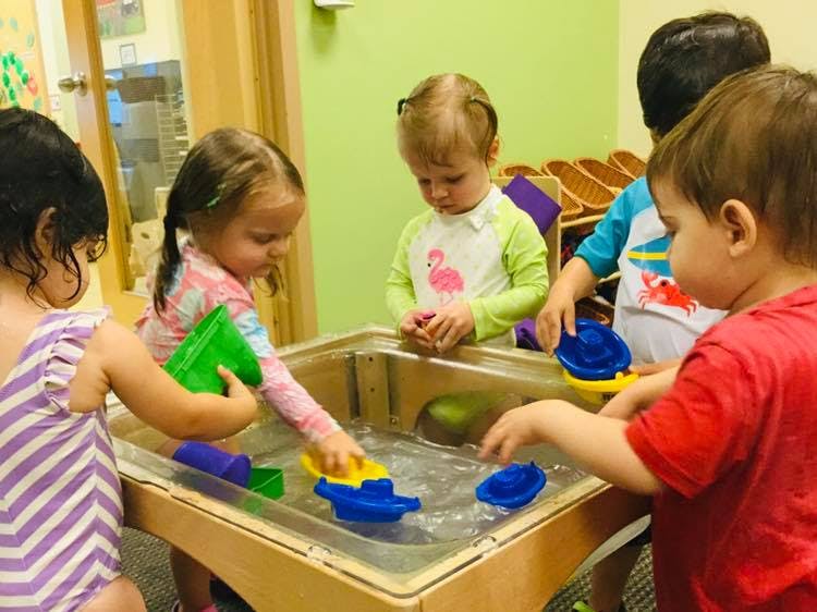 Children playing with boats in a water table