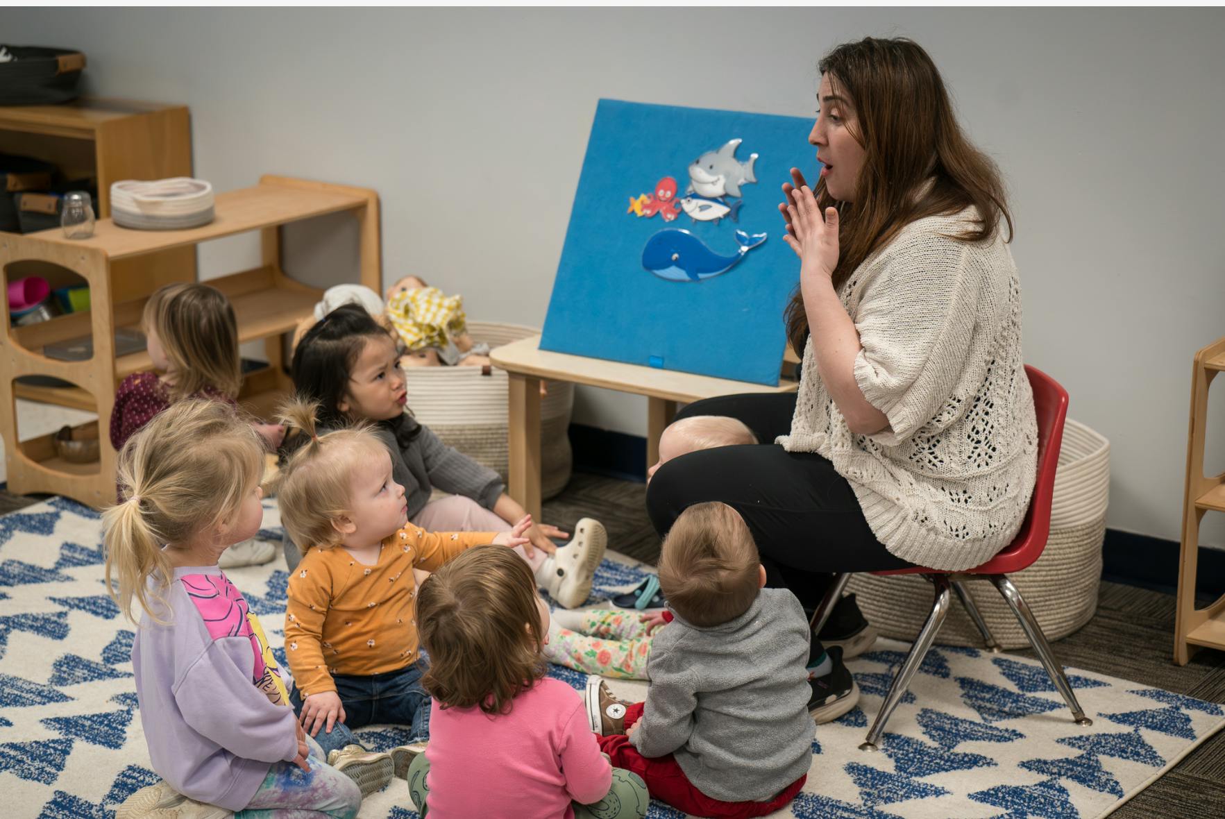 Person reading a book to children in a classroom