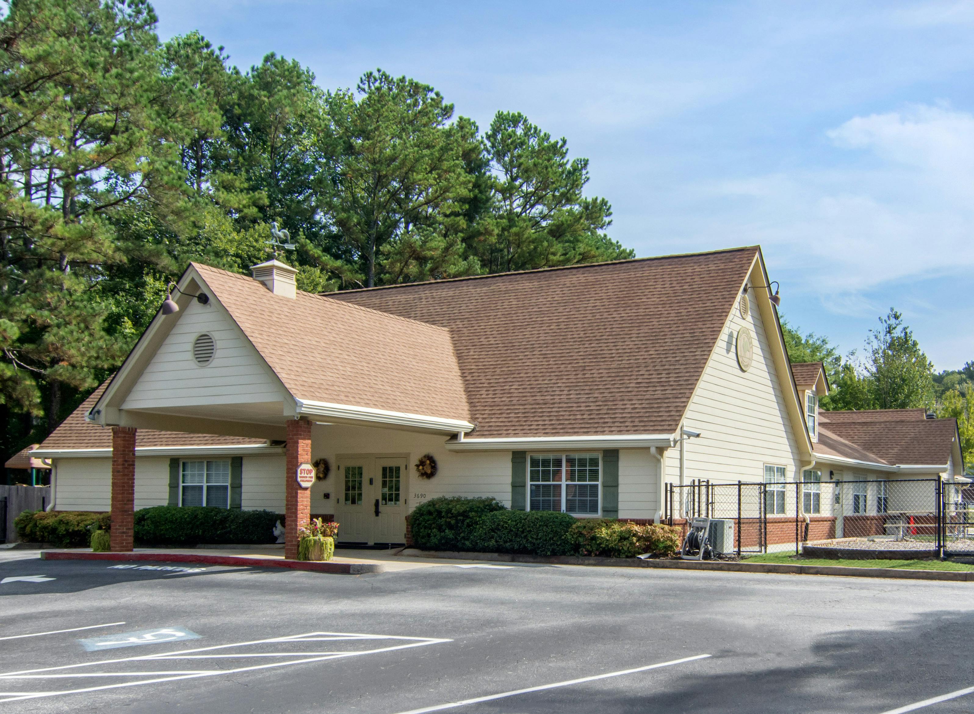 Single-story building with light-colored siding, brown roof, and covered entrance