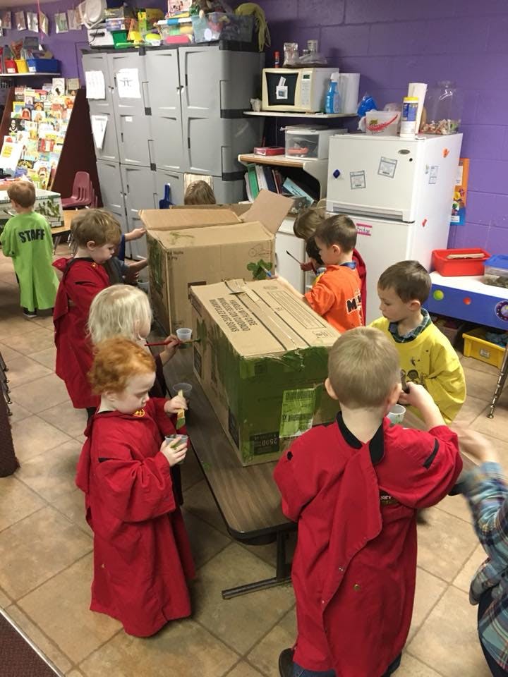 Children playing with cardboard boxes in a classroom