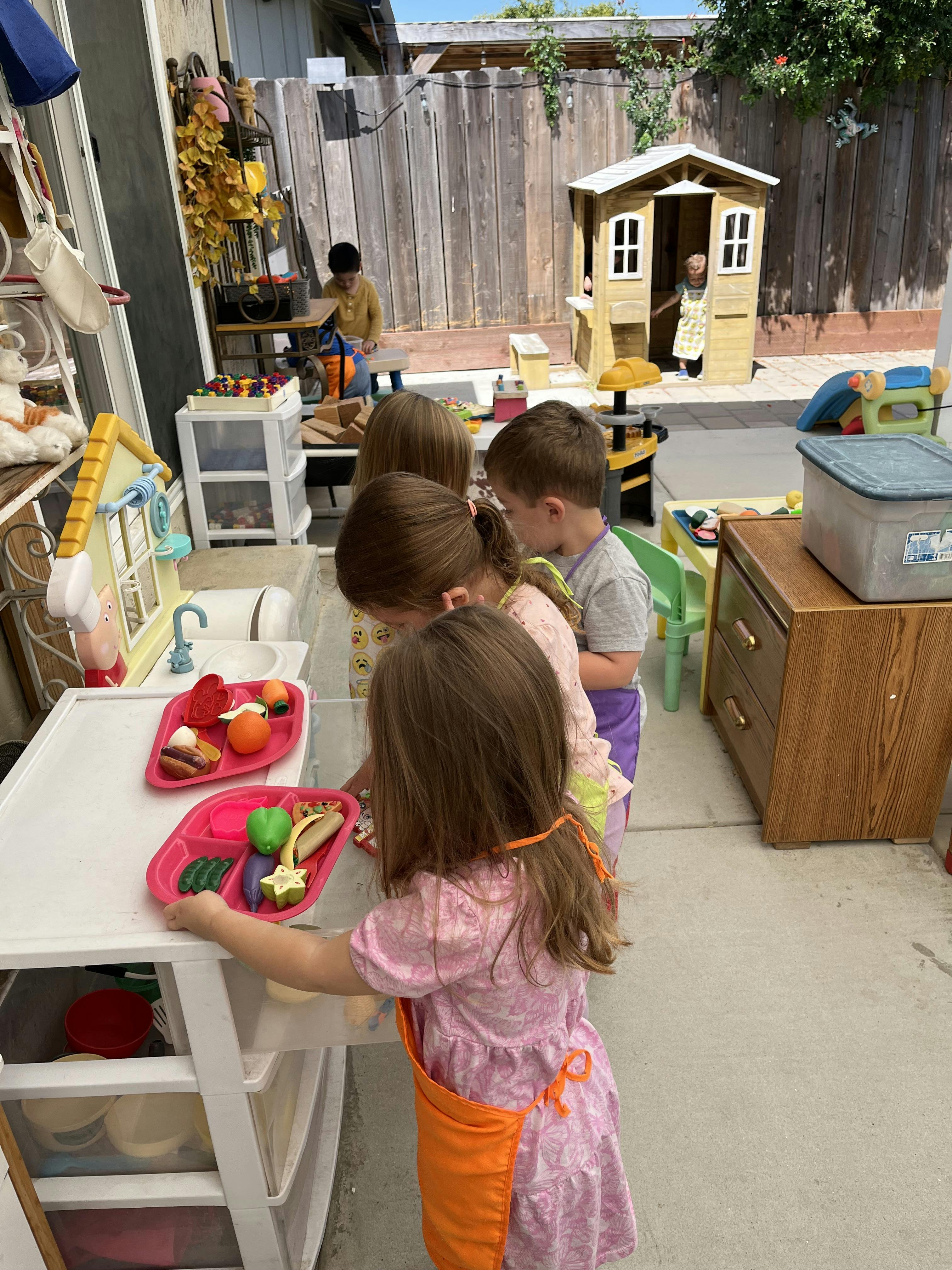 Children playing with toy food and kitchen set outdoors
