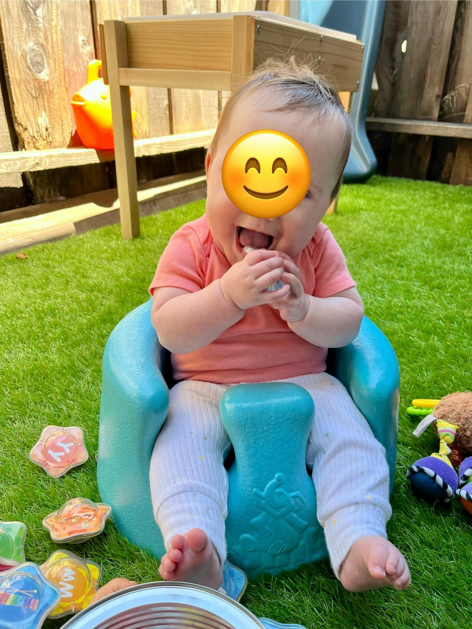 Child sitting in a blue baby seat on grass