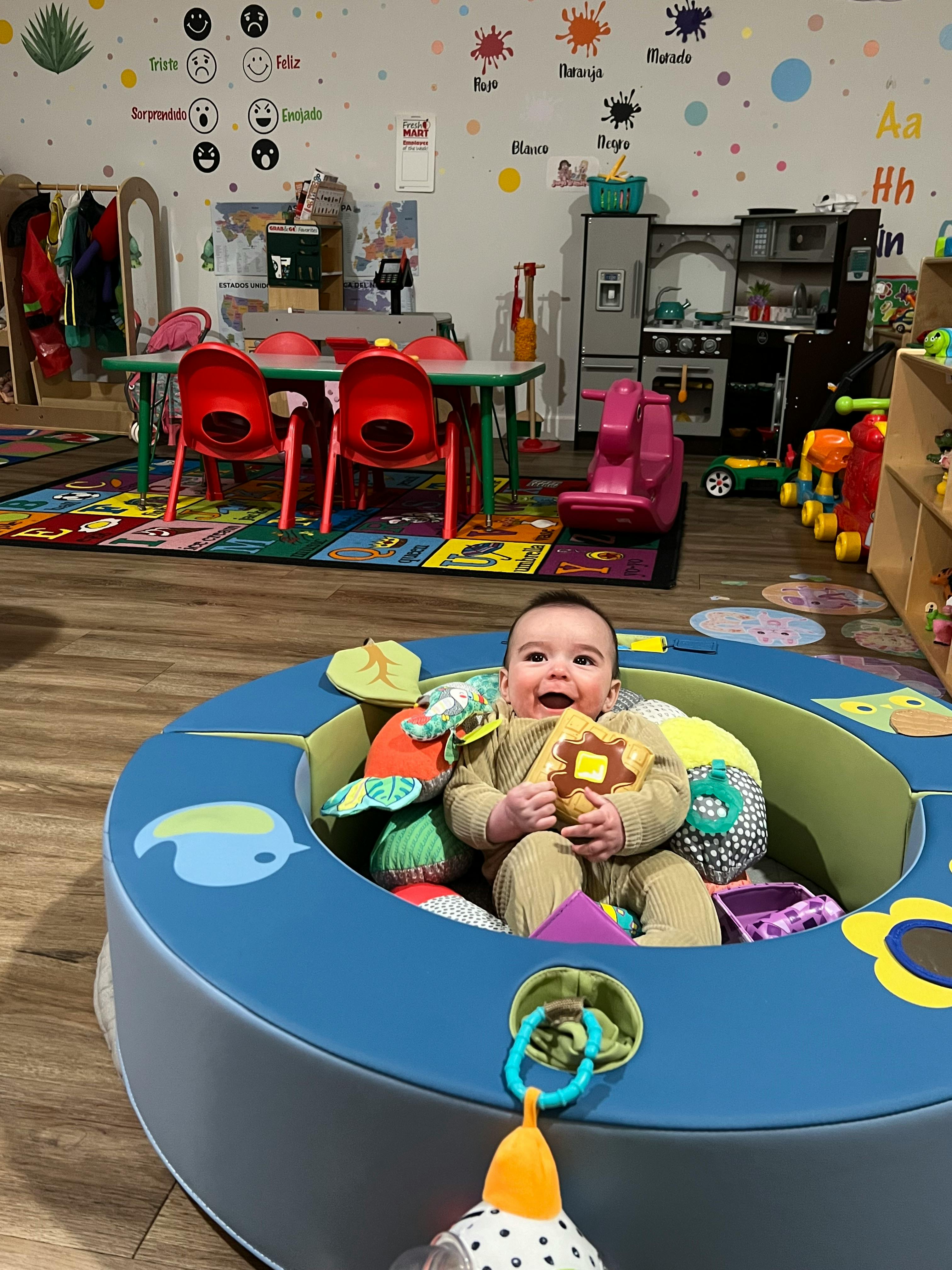 Child sitting in a playpen with toys