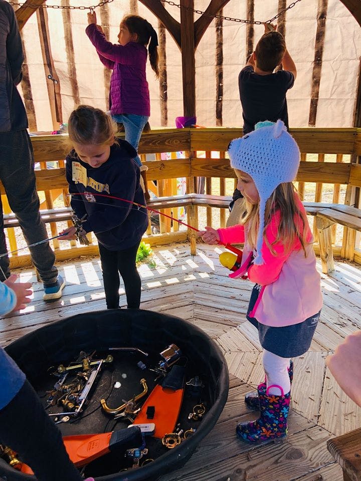 Children playing with fishing rods over a bin of objects