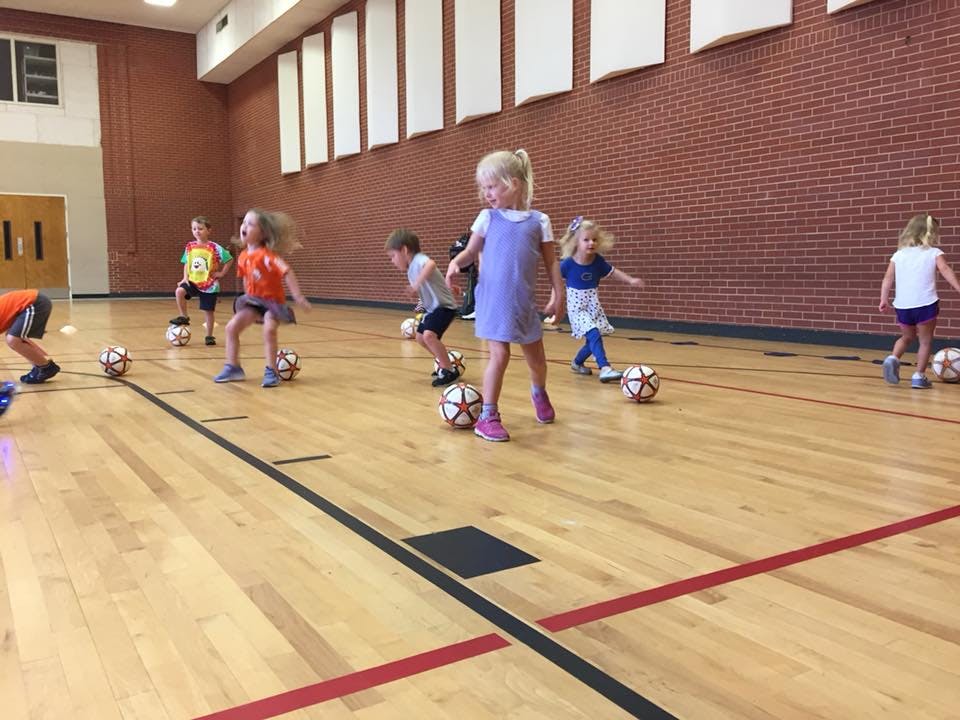 Children playing soccer in a gym