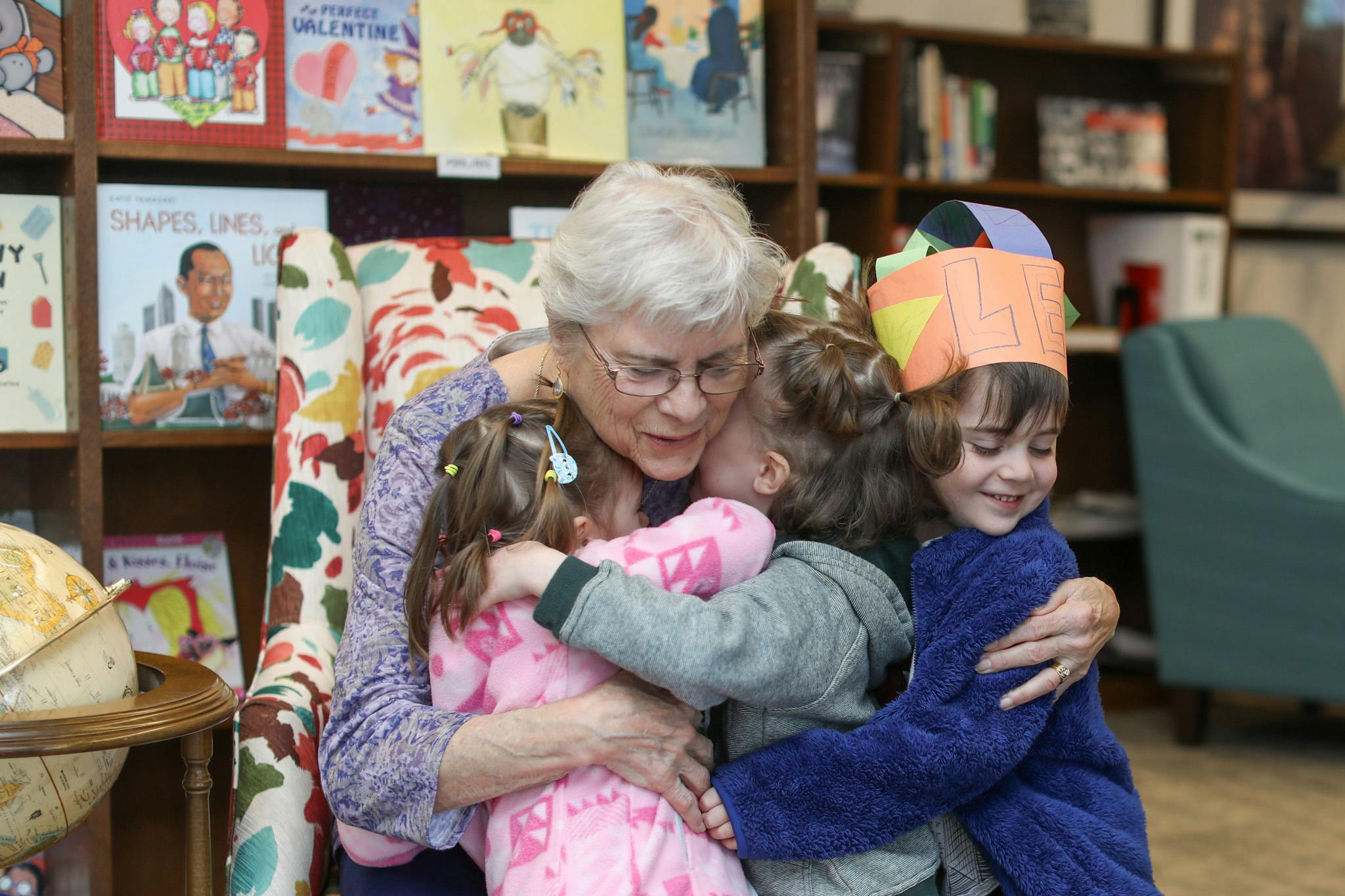 Older person embracing two children and a child in a paper crown