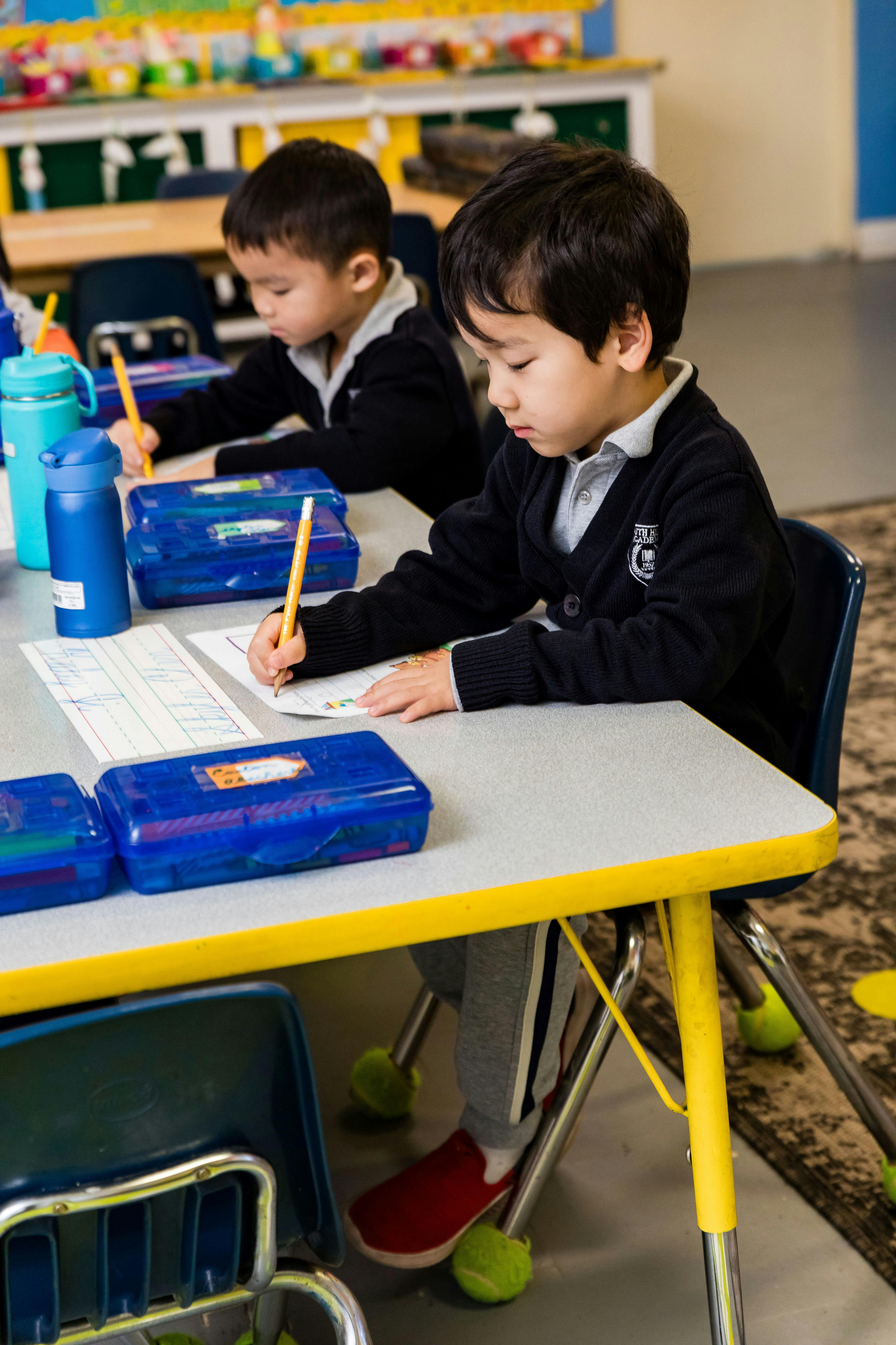 Two children writing at desks in a classroom