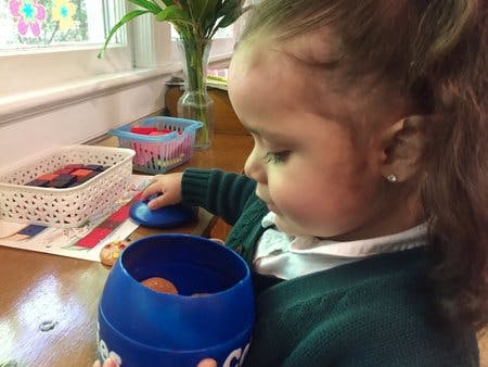 Child holding a blue container with an object inside