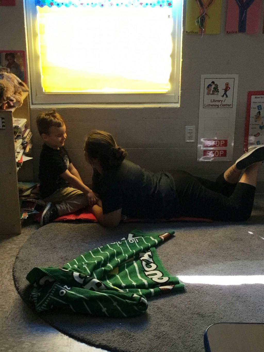 Person lying on stomach talking to a child sitting on the floor