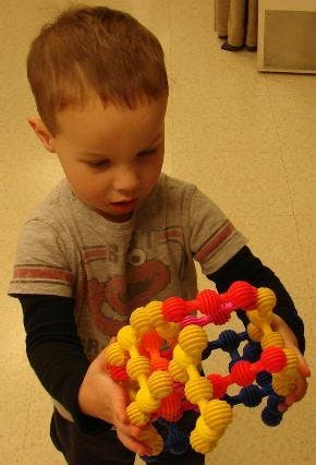 Child holding a colorful toy made of interconnected pieces