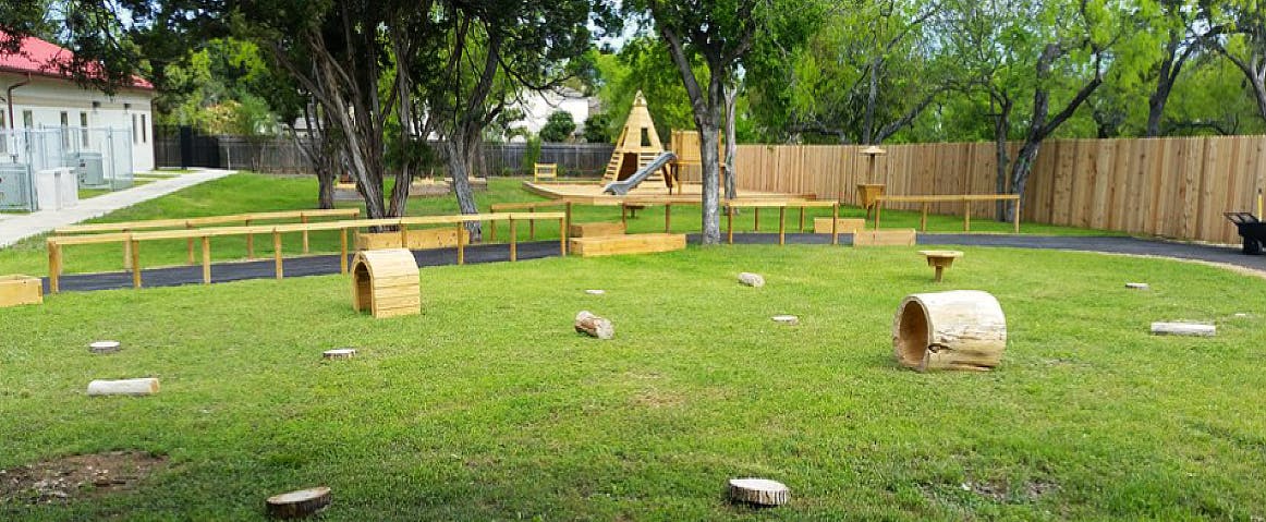 Outdoor playground with wooden structures and green grass