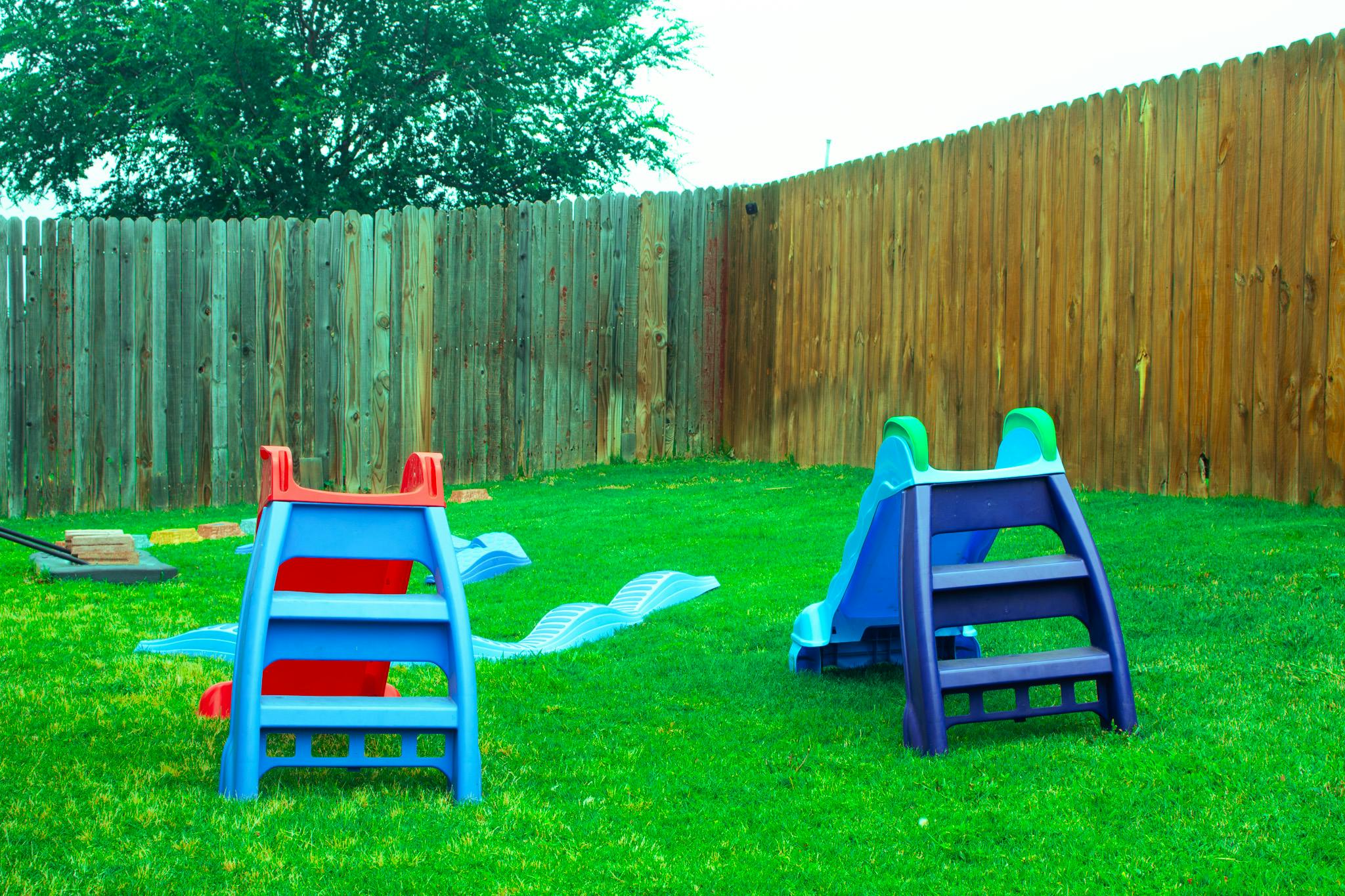Plastic slides and a fence in a backyard
