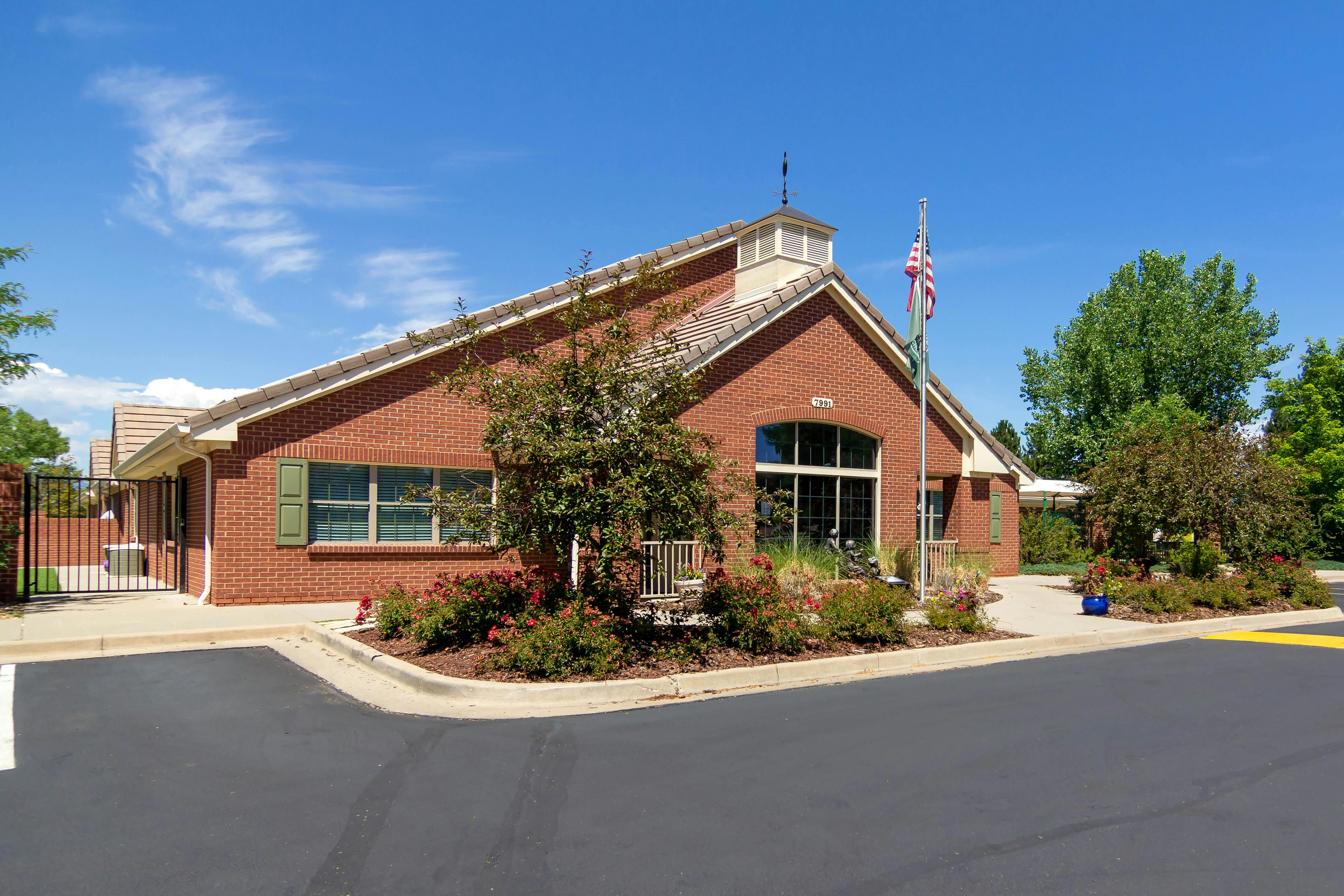 Brick building with a large arched window, an American flag, and landscaping