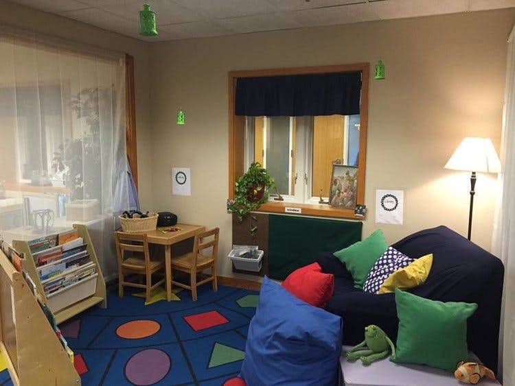Children's reading nook with small table and chairs, bookshelf, and beanbag chairs