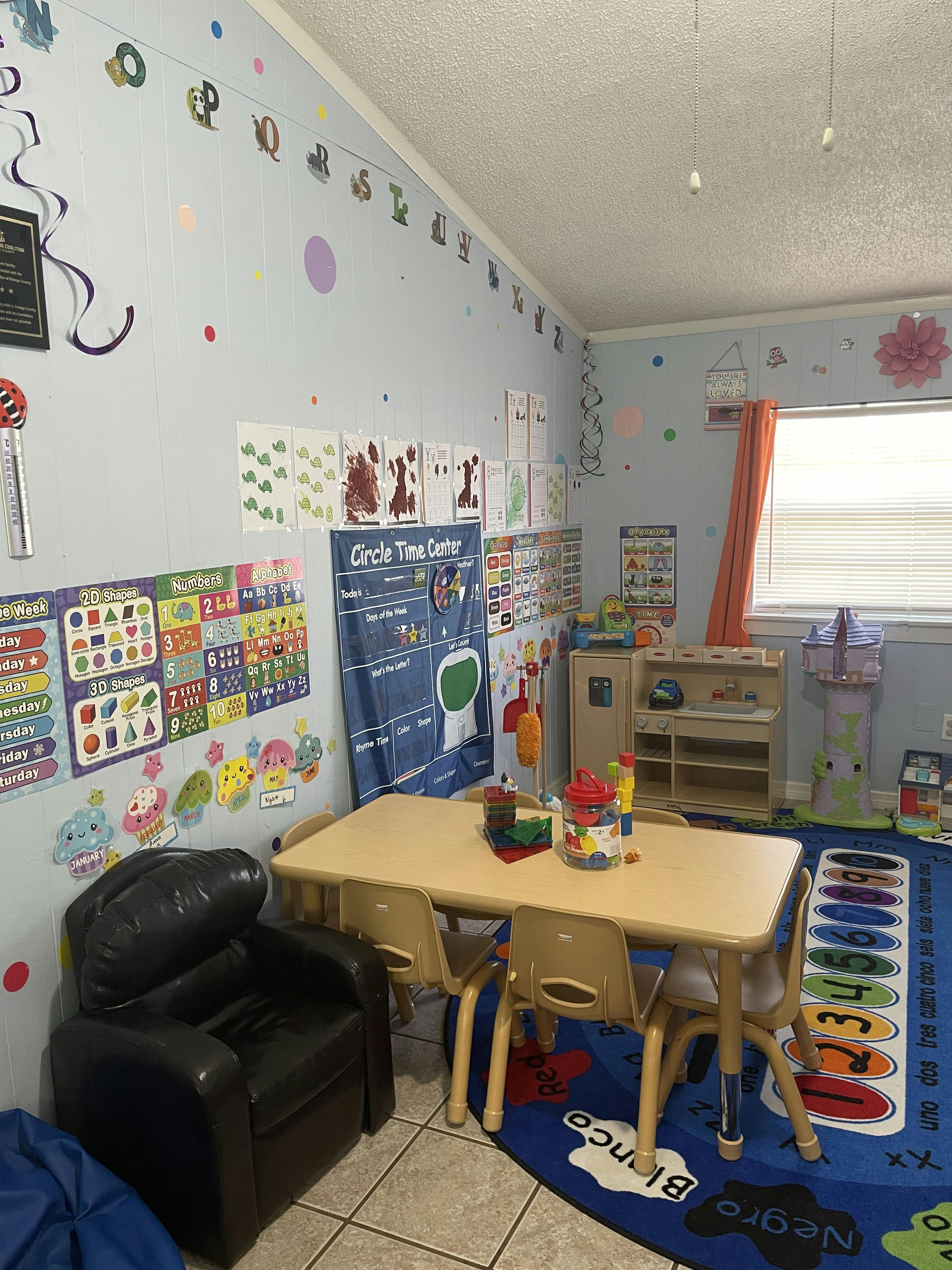 Classroom with small tables and chairs, educational posters on walls