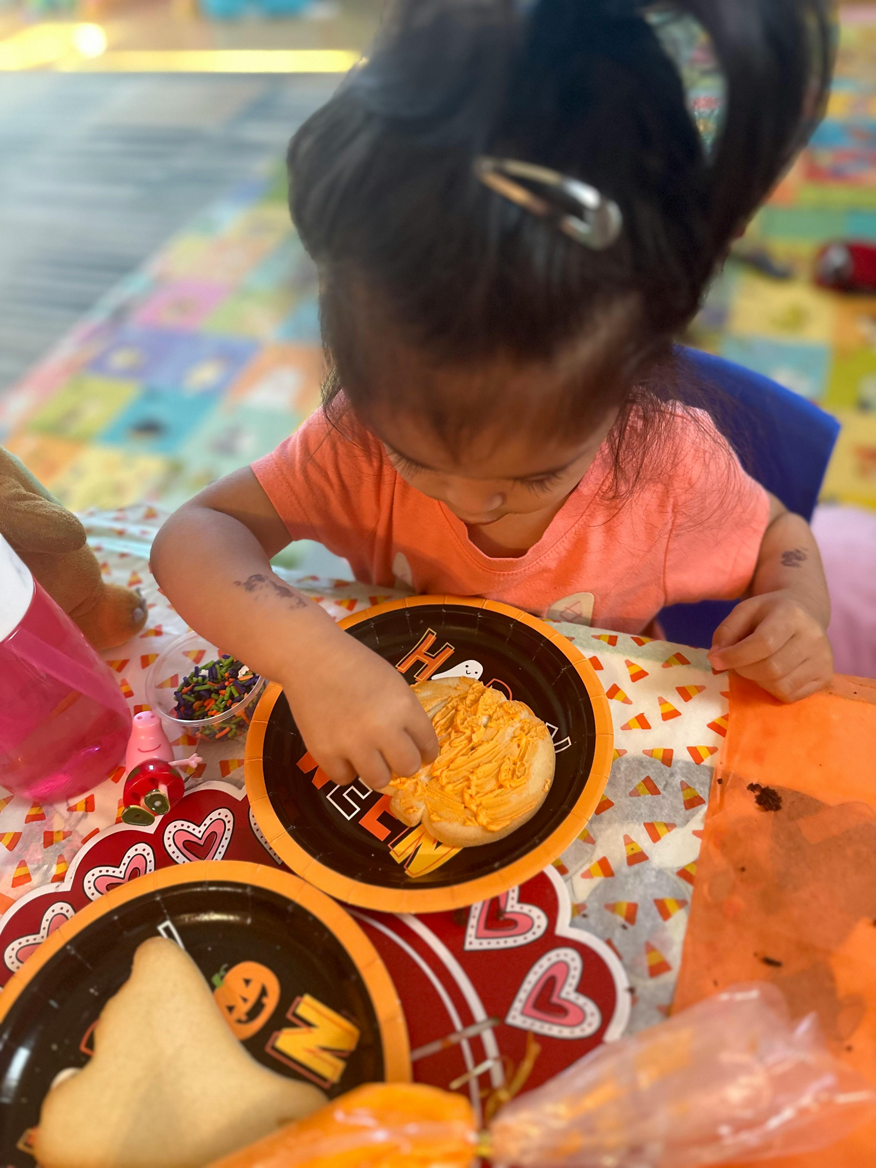 Child eating a cookie from a Halloween-themed plate